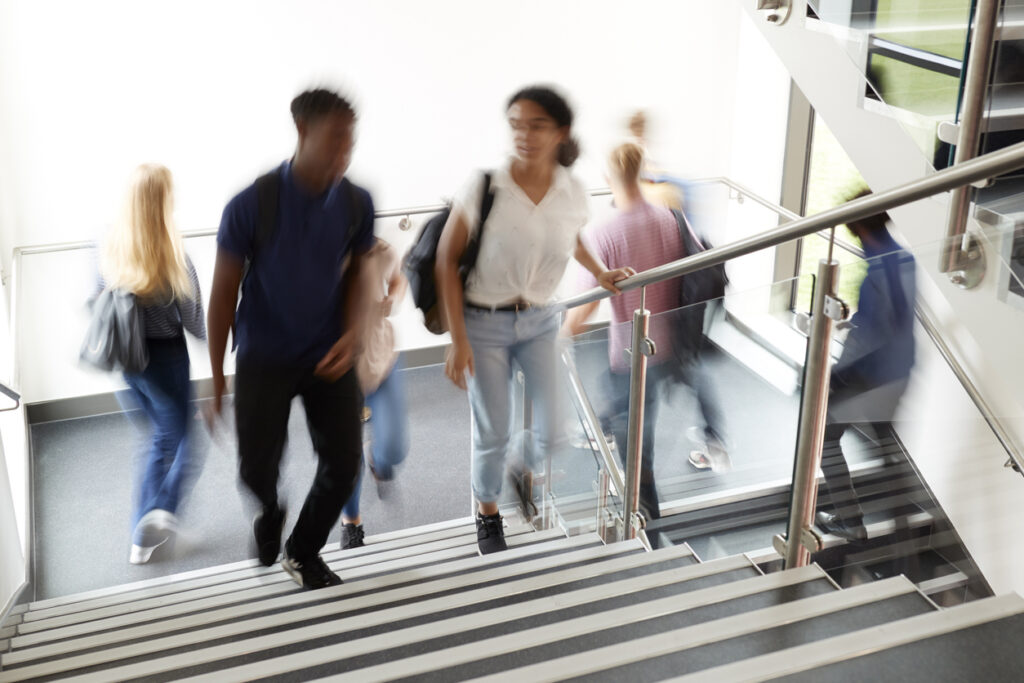 High School Students Walking On Stairs Between Lessons In Busy College Building